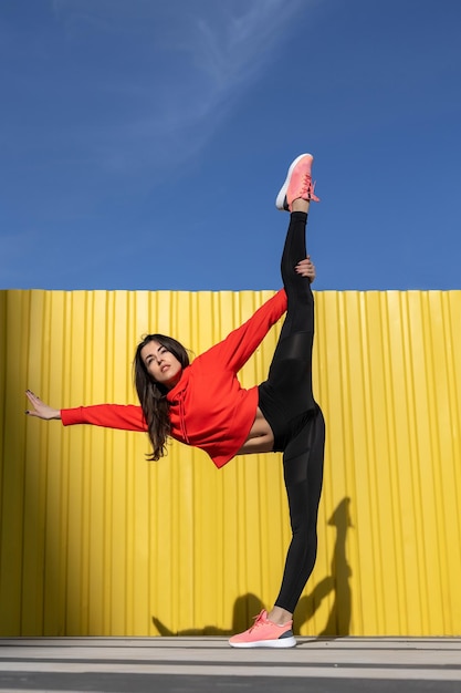 Fitness mujer es fitness estiramiento y ejercicio al aire libre en un entorno urbano de pared amarilla