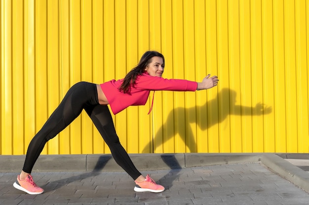 Fitness mujer es fitness estiramiento y ejercicio al aire libre en un entorno urbano de pared amarilla