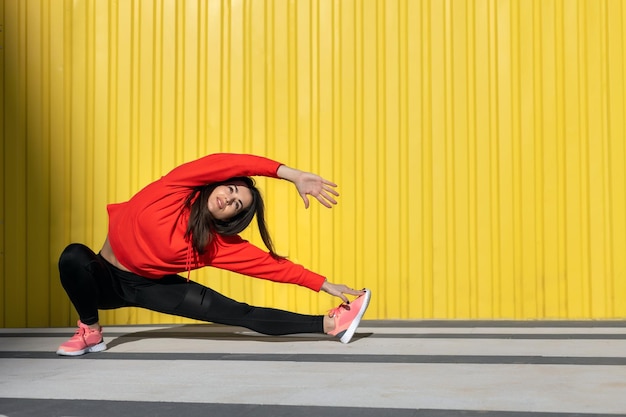 Fitness mujer es fitness estiramiento y ejercicio al aire libre en un entorno urbano de pared amarilla