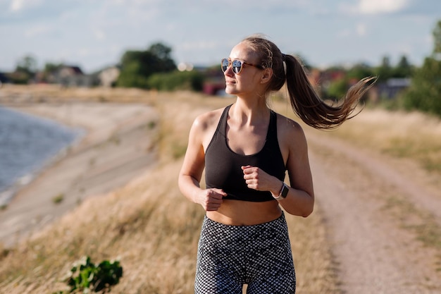 Fitness mujer está trotando por la mañana en la orilla del lago