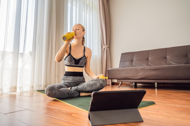 Fitness mujer haciendo ejercicio en el suelo en casa y viendo videos de fitness en una tableta La gente hace deportes en línea debido al coronovirus