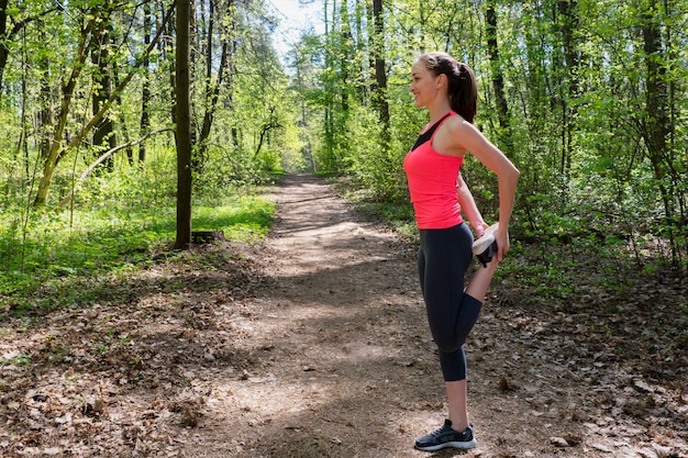 Fitness mujer haciendo estiramientos de piernas antes de correr en el bosque