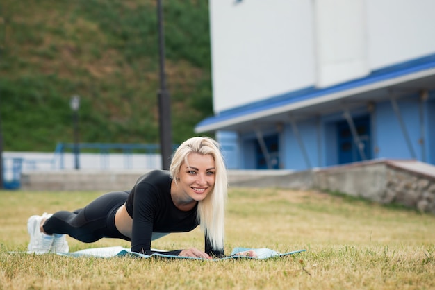 Fitness mujer hermosa en una ropa deportiva haciendo ejercicio de tablón al aire libre. Estilo de vida saludable
