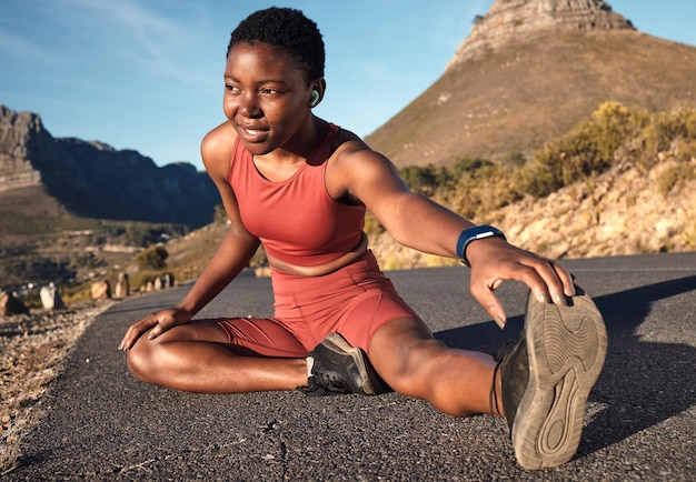 Fitness mujer negra y estirar las piernas en la carretera urbana de montaña y Ciudad del Cabo para el bienestar muscular, el cuerpo sano o el poder. El atleta se calienta y se concentra para hacer ejercicio cardiovascular o correr en la naturaleza.