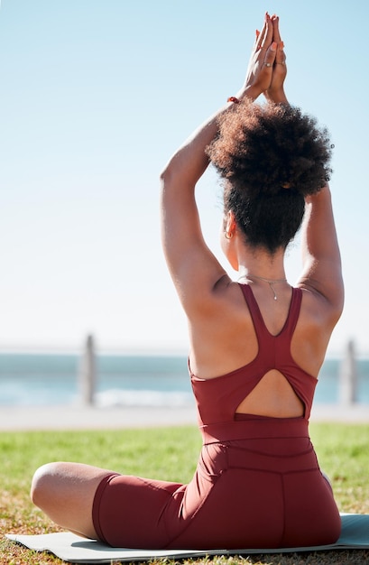 Fitness mujer negra y meditación en colchoneta de yoga en la playa para el bienestar espiritual o ejercicio en la naturaleza Yogui femenina deportiva de vuelta en el estiramiento del brazo de calentamiento para el entrenamiento zen relajación o conciencia en la meditación