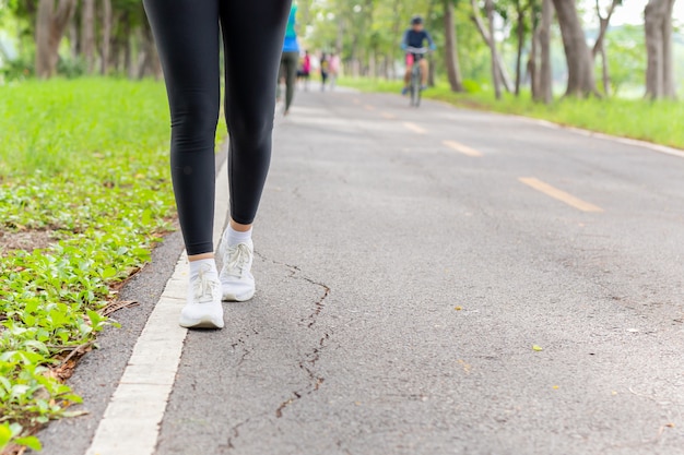 Fitness mujer piernas ejercicio caminando por el sendero del parque en la mañana.