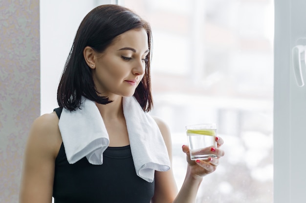 Foto fitness mujer en ropa deportiva con vaso de agua y limón