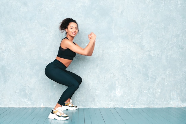 Fitness mujer sonriente en ropa deportiva con peinado de rizos afro