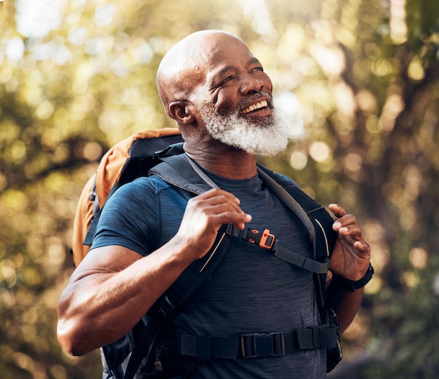 Fitness natural y hombre negro caminando con una mochila en un bosque para hacer ejercicio, salud y bienestar Atleta deportivo y feliz excursionista africano senior caminando en el bosque en un sendero de aventura