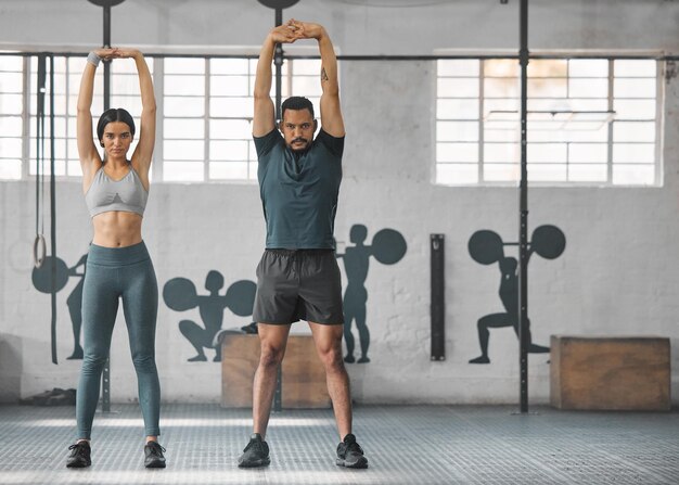 Fitness pareja activa y saludable estirando el ejercicio o entrenando juntos dentro del gimnasio Dos jóvenes entrenadores haciendo un ejercicio de entrenamiento de cuerpo completo o una rutina de calentamiento durante el día con espacio para copiar