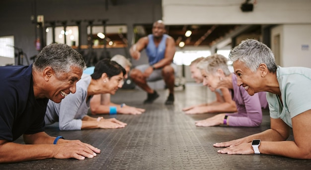 Fitness de personas mayores y tablón con entrenador personal en clase para ejercicios básicos de entrenamiento o entrenamiento en el gimnasio Grupo de ancianos en sesión de entrenamiento abdominal para músculos abdominales fuertes en el piso del gimnasio