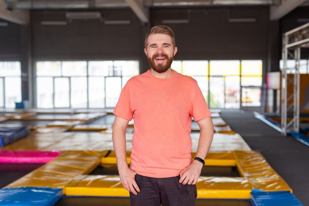 Fitness-, Spaß-, Freizeit- und Sportaktivitätskonzept - Mann, der auf einem Trampolin drinnen lächelt