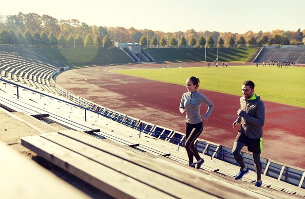 Fitness, Sport, Bewegung und Lebensstil - ein glückliches Paar läuft auf der Oberseite des Stadions