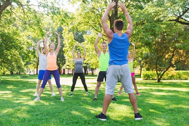 fitness, sport, freundschaft und gesundes lebensstilkonzept - gruppe glücklicher jugendlicher freunde oder sportler, die im bootcamp trainieren