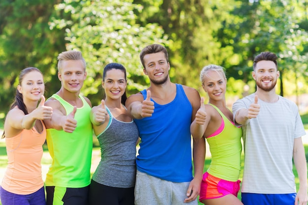 fitness, sport, freundschaft und gesundes lebensstilkonzept - gruppe glücklicher jugendlicher freunde oder sportler, die im freien daumen hoch zeigen