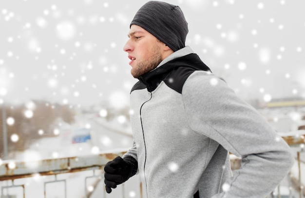 Fitness, Sport, Menschen, Jahreszeit und gesundes Lebensstil Konzept - junger Mann läuft entlang der Winterbrücke