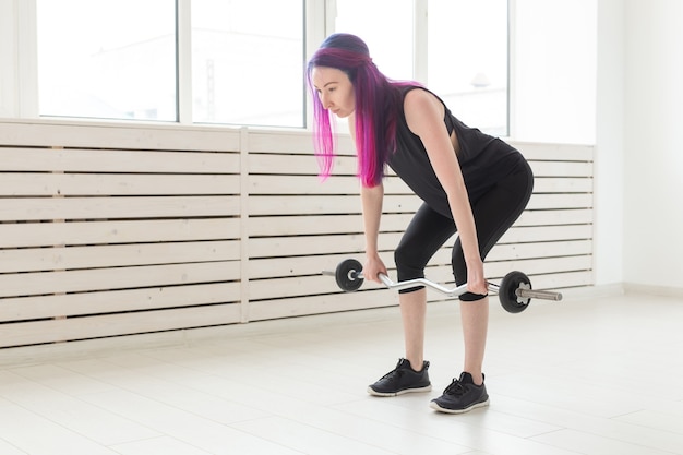 Fitness, Sport, Menschen Konzept - junge Frau im Sportanzug hockt mit Bar.