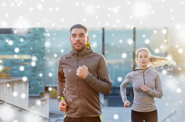 Fitness-, Sport-, Menschen-, Trainings- und gesundes Lebensstilkonzept – glückliches Sportlerpaar läuft auf Stadttreppen über Schnee nach oben
