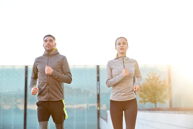 Fitness-, Sport-, Menschen-, Trainings- und Lifestyle-Konzept - glückliches Paar, das auf der Treppe der Stadt nach oben läuft