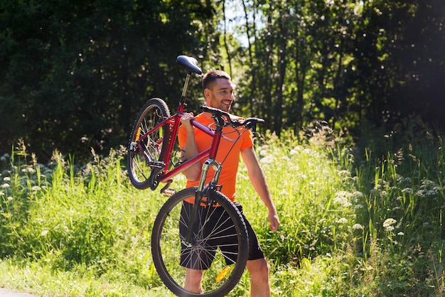 Fitness, Sport, Menschen und gesundes Lebensstilkonzept - glücklicher junger Mann, der draußen Fahrrad fährt