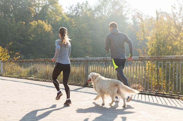 Fitness-, Sport-, Menschen- und Joggingkonzept - Nahaufnahme eines Paares mit Hund, das im Freien läuft