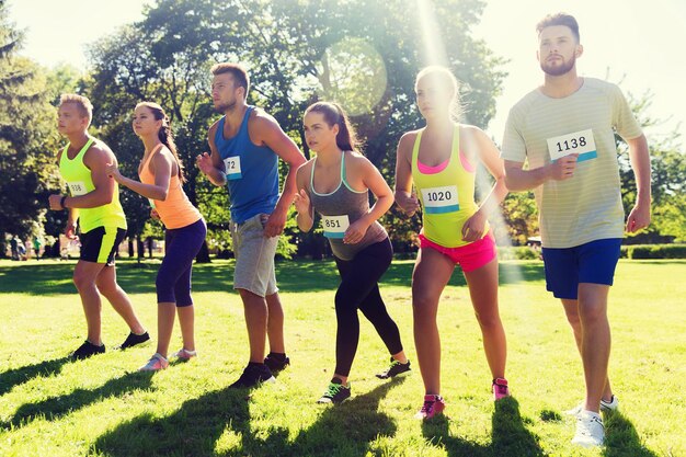 Fitness-, Sport-, Renn- und gesundes Lifestyle-Konzept - Gruppe von Teenager-Freunden oder Sportlern mit Abzeichennummern beim Start des Marathonlaufs im Freien
