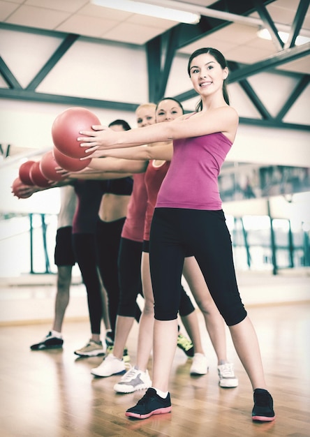 Fitness-, Sport-, Trainings-, Fitness- und Lifestyle-Konzept - Gruppe lächelnder Menschen, die mit Gymnastikbällen im Fitnessstudio trainieren