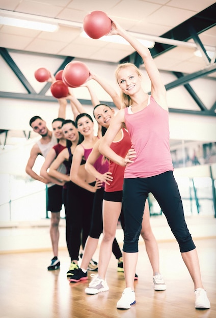 Fitness-, Sport-, Trainings-, Fitness- und Lifestyle-Konzept - Gruppe lächelnder Menschen, die mit Gymnastikbällen im Fitnessstudio trainieren