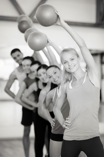 Fitness-, Sport-, Trainings-, Fitness- und Lifestyle-Konzept - Gruppe lächelnder Menschen, die mit Gymnastikbällen im Fitnessstudio trainieren