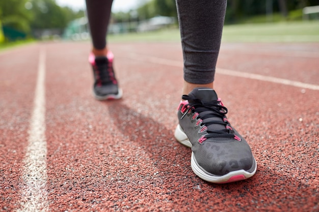 Fitness-, Sport-, Trainings-, People- und Lifestyle-Konzept - Nahaufnahme von Frauenfüßen, die von hinten auf der Strecke laufen