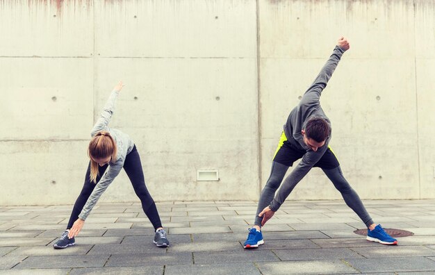 Foto fitness-, sport-, trainings-, trainings- und personenkonzept - nahaufnahme eines paares, das sich auf der stadtstraße dehnt