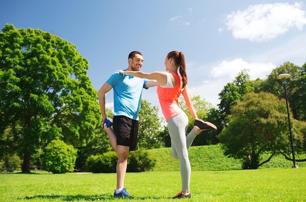 Fitness-, Sport-, Trainings- und Lifestyle-Konzept - lächelndes Paar, das sich im Freien ausdehnt