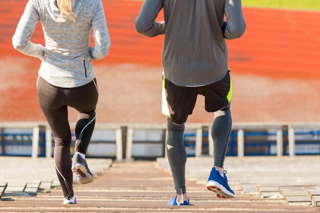 Fitness-, Sport-, Trainings- und Lifestyle-Konzept - Nahaufnahme eines Paares, das die Treppe hinunter auf das Stadion läuft