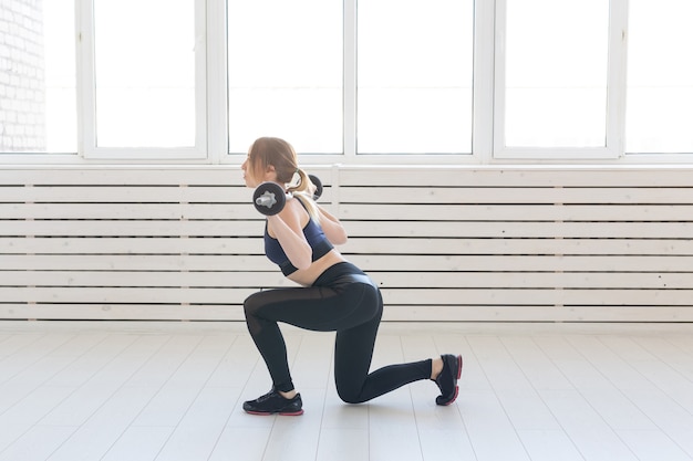 Fitness-, Sport- und People-Konzept - lächelnde sportliche Frau mit Langhantel, die Split Squat oder Longe macht.