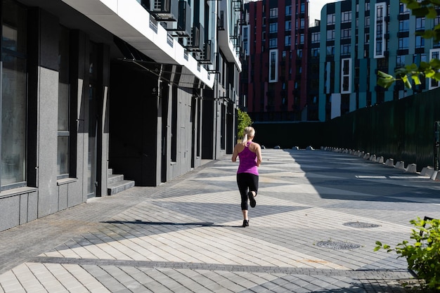 Fitness-Sportlerin in modischer Sportbekleidung, die Yoga-Fitness-Übungen auf der Straße macht, Sport im Freien, urbaner Stil