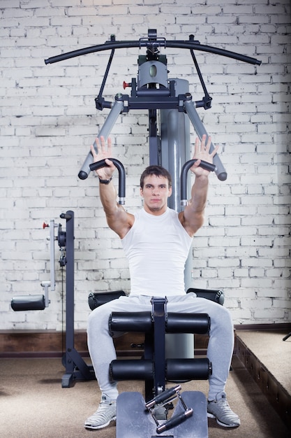 Fitness - starker muskulöser Mann, der Gewichtheben im Fitnessstudio tut