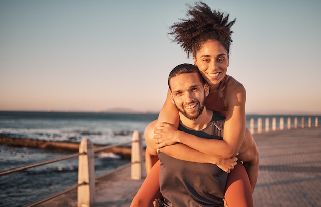 Fitness-Strand und Porträt eines Paares huckepack genießen Urlaub und schöne Zeit am Wochenende Lieben Sie den Sommer und schwarze Männer und Frauen entspannen sich nach dem Lauftraining und Training am Meer