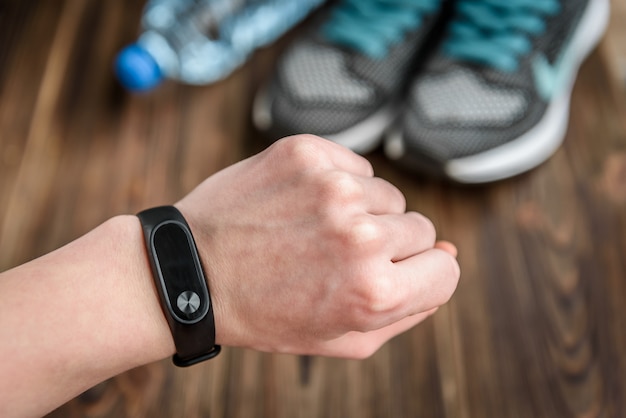 Fitness-Tracker und Turnschuhe auf Holztisch.