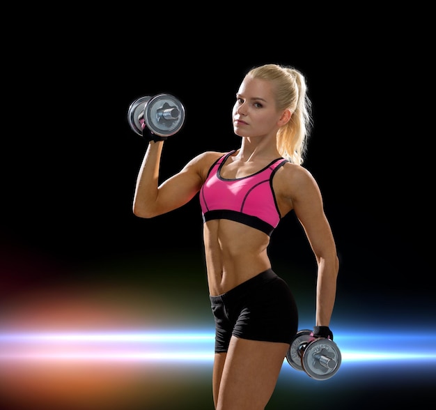 Fitness-, Trainings- und Diätkonzept - sportliche Frau mit schweren Stahlhanteln