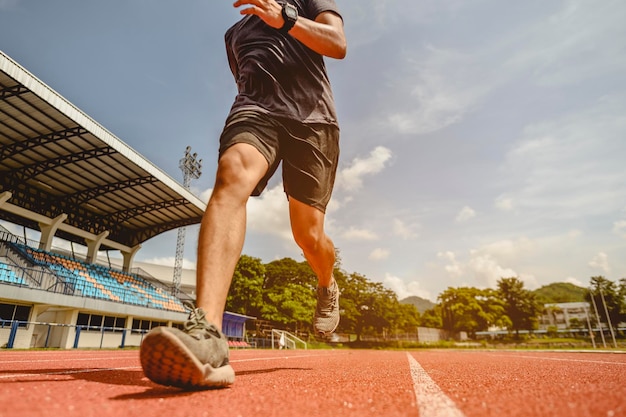 Fitness, trotar, correr, ejercicio, estilo de vida y concepto saludable. El joven usó todas las partes de su cuerpo para prepararse para trotar en la pista de atletismo alrededor del campo de fútbol.