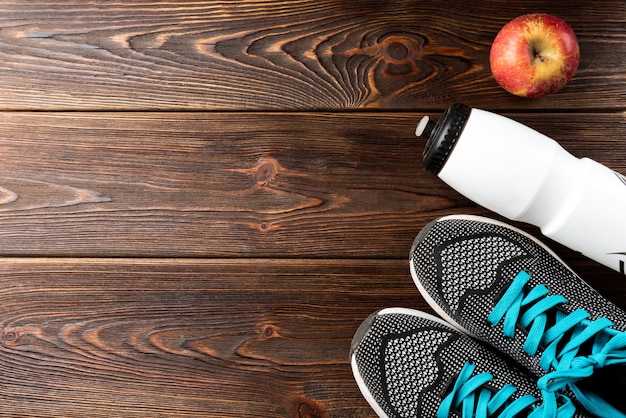 Fitness-Turnschuhe, eine Flasche Wasser und Apfel