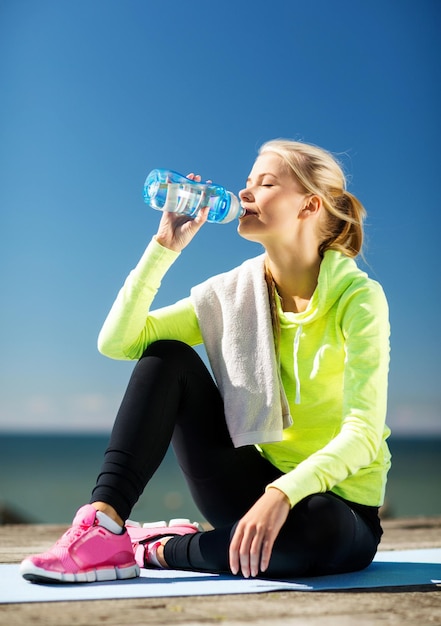 Fitness- und Lifestyle-Konzept - Frau trinkt Wasser nach Sport im Freien