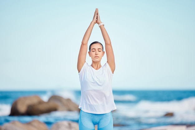 Fitness de yoga y mujer en la playa para hacer ejercicio o entrenar como rutina de salud y bienestar El cuerpo sano y la persona ejercitan un chakra haciendo pose de árbol en el mar o en la naturaleza