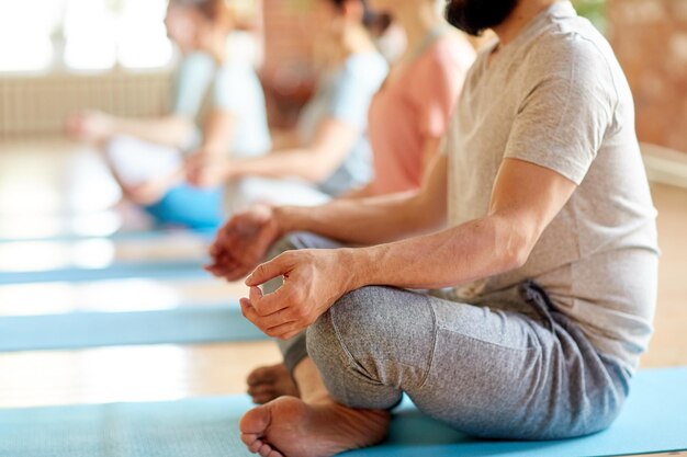 Foto fitness-, yoga- und gesunde lebensstilkonzept - eine gruppe von menschen meditiert in der lotus-position im studio