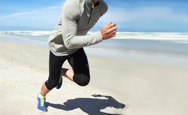 Fitnessfanatiker Schnappschuss eines Mannes, der am Strand entlang läuft