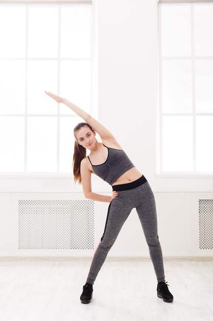 Fitnessfrau beim Dehnungstraining drinnen