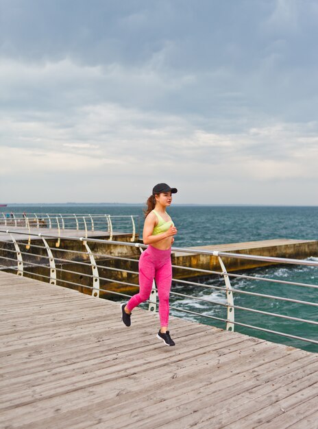 Fitnessfrau in Sportbekleidung läuft am Strand.