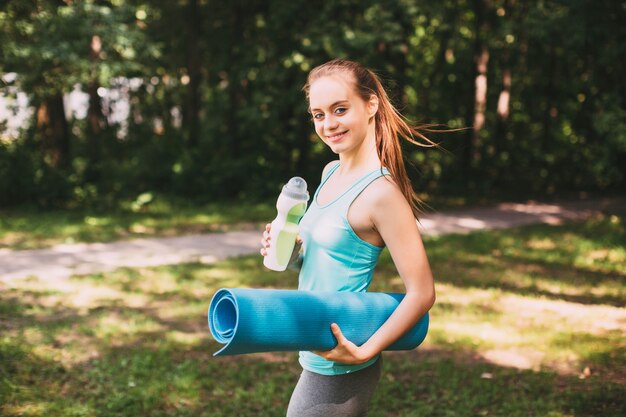 Fitnessfrau mit Yogamatte im Freien