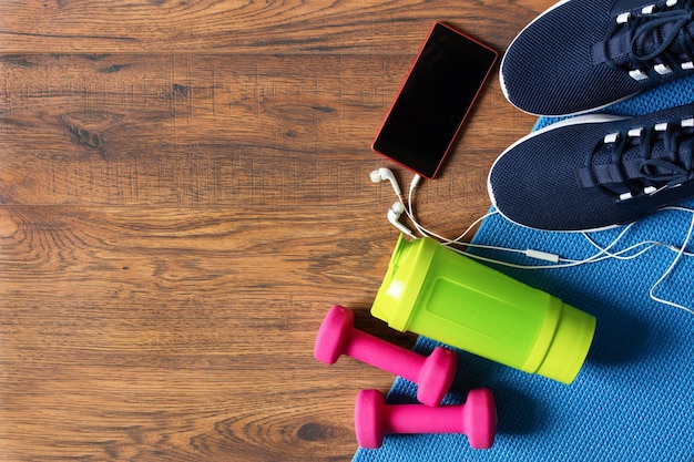 Fitnessgeräte Draufsicht mit Kopierbereich Hanteln Wasserflasche Sportschuhe und Fitnessmatte