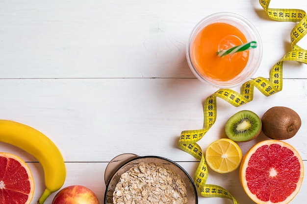 Fitnesskonzept mit Obst, einem Glas Saft und Zentimeter-Draufsicht-Hintergrundkonzept